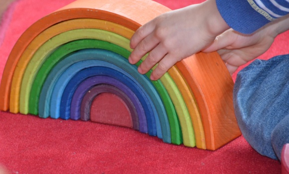 Regenbogenmaterial mit Kinderhand