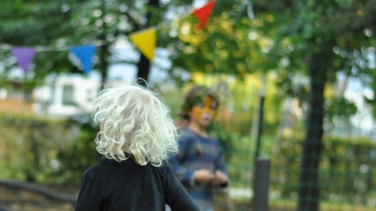 Kind von hinten rennend im Garten unter einer Wimpelkette.